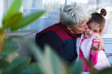 Happy family, generation and people concept - happy smiling young tree years old granddaughter with senior grandmother standing by House at Autumn Season, hugging in Oregon USA close-up portrait 