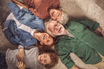Top view portrait of cheerful bearded grandfather with happy wife and outgoing daughter with...