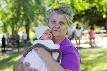 Close-up Portrait of  Beautiful Grandmother Holding Her Newborn Baby Girl Granddaughter  at Hot Summer Day, Park, Family Vacation, Oregon USA, Happy Granny Concept, Happy Family Concept