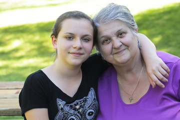 Happy family, generation and people concept - happy smiling young twelve years old granddaughter with senior grandmother standing  at Summer Park , hugging in Oregon USA close-up portrait 