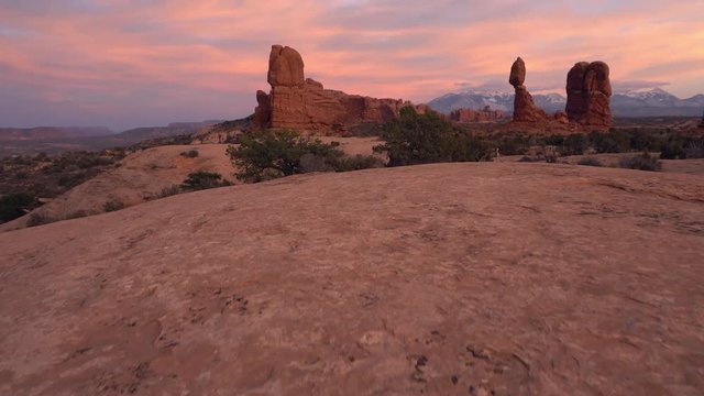 Walking towards Balanced Rock during colorful sunset in Arches NP in Utah.