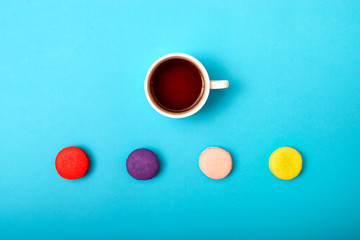 Colorful sweet macaroons and a cup of tea. Delicious breakfast. Top view.	