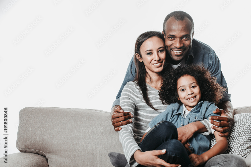 Aufkleber portrait of african family looking at camera with joy while reposing on sofa with coziness. copy spa