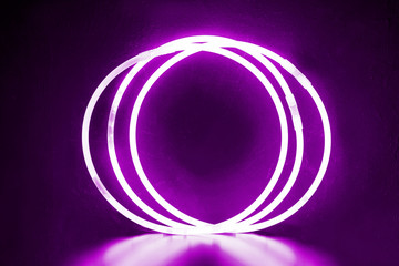 violet round bracelets/ Three round bracelets of glow sticks of pink ultra violet with neon glow. With reflection on a black background