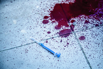 Used syringe and blood on the floor as symbol of narcotism and drug addiction.