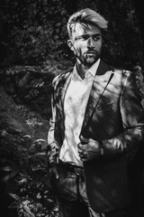 Fototapeta na wymiar Brutal young man with beard and gray. Stylish Afghan man in jacket costume on the nordic Karelian nature landscape background. Marble Canyon and Dramatic sky in Karelia republic. Karelian forest. BW