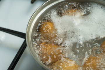 Chicken eggs boil in water. Pan with the product on a gas stove.