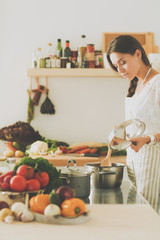 Cooking woman in kitchen with wooden spoon. Cooking woman