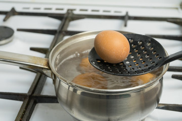 Chicken eggs boil in water. Pan with the product on a gas stove.