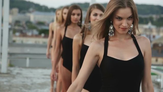 six attractive girls models black bodysuit heels walking outside roof building midnight light up colored smoke bomb slow motion fashion athletic human body figure stylish women earrings accessories