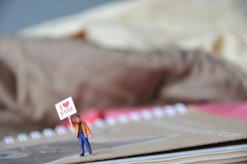 Miniature man holding of I love you message in the paper with beautiful background, special word about feeling love for valentine’s day, love message for everyone in special day. love greeting concept