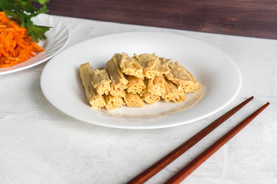 Tofu skin (yuba sticks or Fuzhu) and chopsticks on a concrete table. Healthy asian soy food.