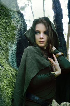 she-elf dressed in cloak with hood color of khaki in a dense the forest