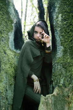 she-elf dressed in cloak with hood color of khaki in a dense the forest