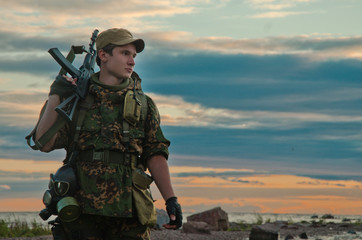 soldier with rifle against the setting sky-toned image