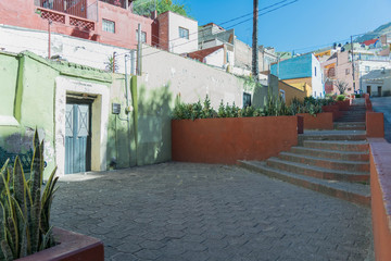 A neighborhood with colorful houses, paving stones, stone steps, plants and other architectural details, in Guanajuato, Mexico - 191813051