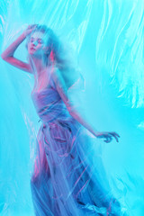 Obraz na płótnie Canvas Fashion portrait of young beautiful woman under polyethylene.