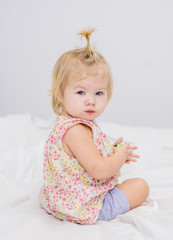 Funny little girl sitting on the bed