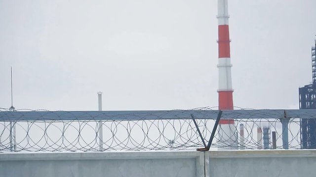 Barbed wire on a concrete fence enclosing an oil refinery