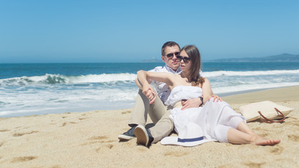 Fototapeta na wymiar Young smiling couple sitting on the beach