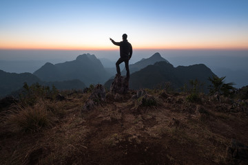 tourist enjoying sunset on top of a mountain. Tourist on the peak of high rocks, Landscape with traveler