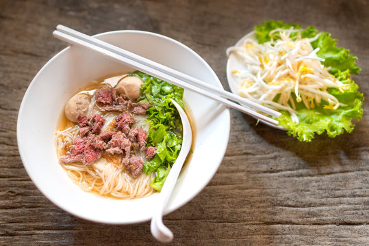 Asian Chinese noodle soup with beef and meatball fresh vegetable on wooden table delicious street food of Thailand