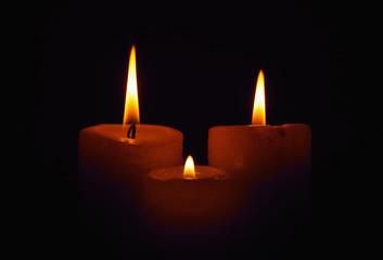 Three burning candles in the darkness