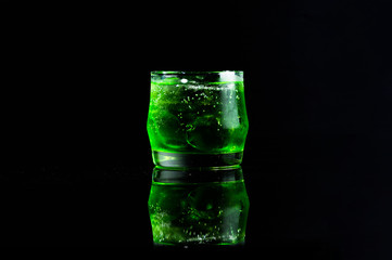 Fresh green italian soda drink with splashing and crushed ice in freeze motion.