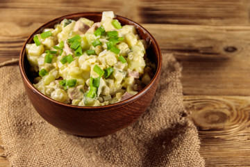 Traditional Russian festive salad Olivier on wooden table
