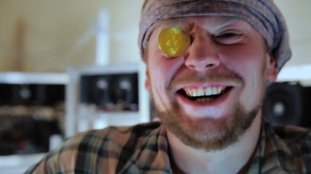 Young cheerful man with golden bitcoin instead of eyeglass posing excitedly at camera.