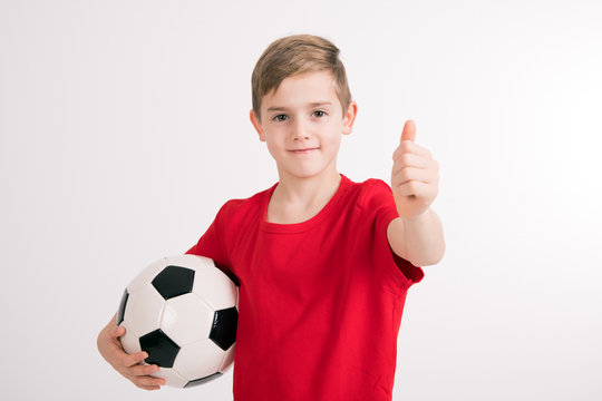boy in red shirt with soccer ball and thumb up