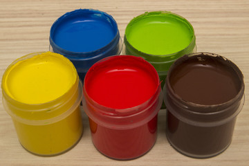 Finger paints in jars on a wooden background