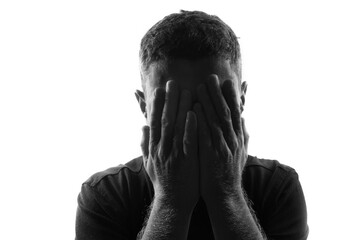 Male person silhouette over white covering his face with hands