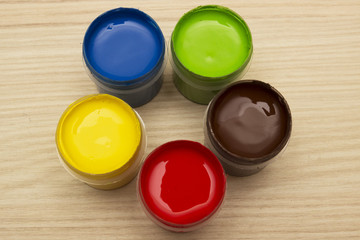 Finger paints in jars on a wooden background