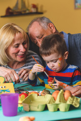 Obraz premium Grandparents with grandson painting eggs for Easter.