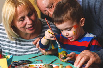 Grandparents with grandson painting eggs for Easter.