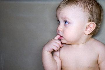 Adorable toddler sucking finger. Little charming baby with bright blue eyes looking distracted away while sucking finger.