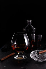 Glass of whiskey with smoking cigar.