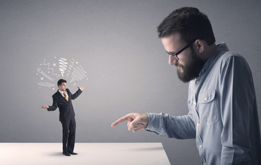 Young businessman fighting with miniature businessman