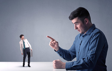Young businessman fighting with miniature businessman