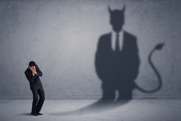 Business man looking at his own devil demon shadow concept