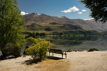 Park bench with mountain reflections on lake
