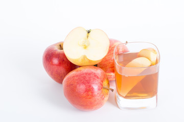 Apple cider vinegar in a glass cup and fresh apples on white background.
