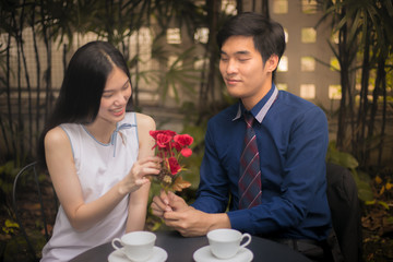 Romance background, couple in love on date, man giving red flowers to his girlfriend.