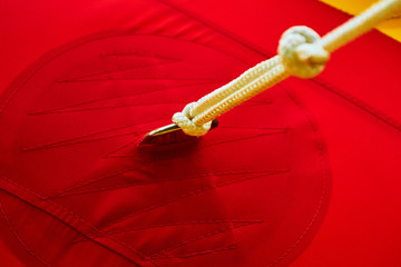 The metal holder for the rope is sewn to the red fabric with threads