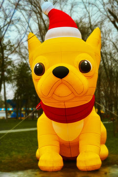A huge inflatable yellow dog stands in a park in a big city