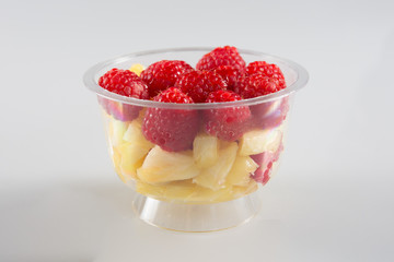 Healthy fruit salad in plastic bowl isolated white