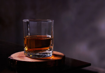 A glass of alcoholic drink on a wooden plate placed of a glass table