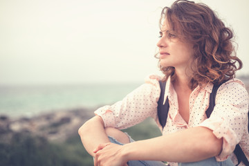 Fototapeta na wymiar Portrait of a beautiful young thoughtful beautiful girl sitting on the beach