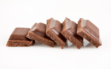 Milk chocolate pieces isolated on white background.